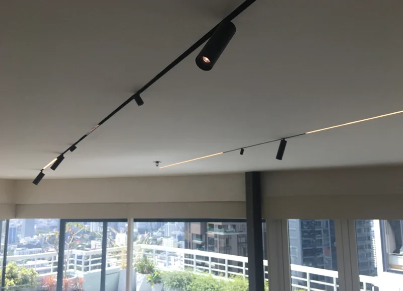 Seamless recessed slim magnetic track lighting with accent spotlights and linear LED strips integrated into a luxury Bangkok living room gypsum ceiling.