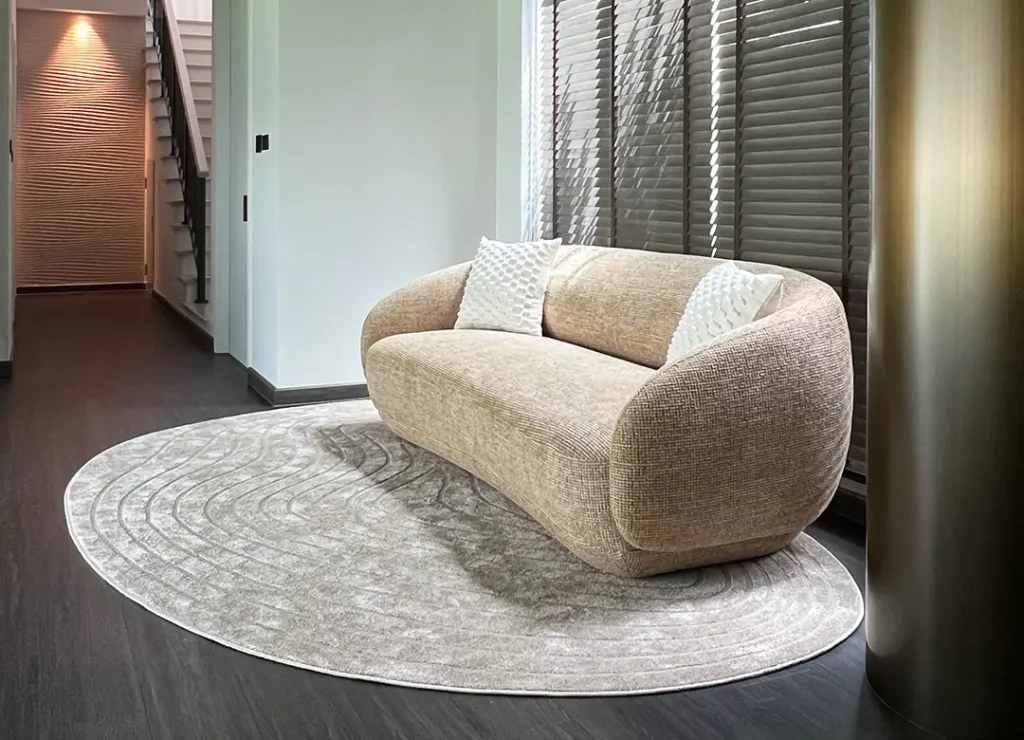 Curved sofa on an organic rug with bronze column and wave accent wall at AIRI Km.5 project by Elementi Interiors