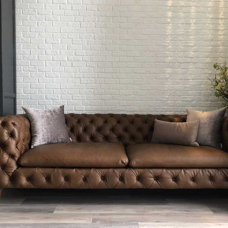 Leather Italian sofa with white brick wall backside